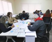 personas alrededor de una mesa conversan. Al medio hay una cartulina donde escriben sus conclusiones